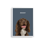 A framed pet portrait print featuring a brown and white dog on a muted blue-gray background with the name 'BROWNY' in white text at the top. The print is shown centered against a clean white background.